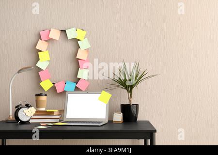 Workplace with blank laptop, sticky notes and alarm clock in office Stock Photo