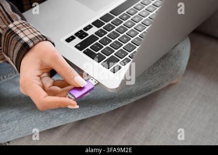 Data transfer and digital storage, woman inserting purple USB flash drive into laptop computer port Stock Photo