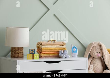 Newborn baby essentials and nursery decor stacked clothes baby monitor and toys on a dresser for infant care Stock Photo