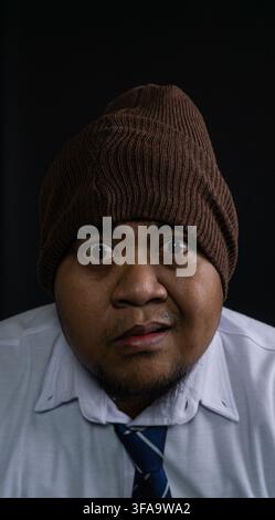A young Southeast Asian male displays a twisted facial expression conveying deep confusion, awkwardness, or mild disgust. The subject stands prominent Stock Photo