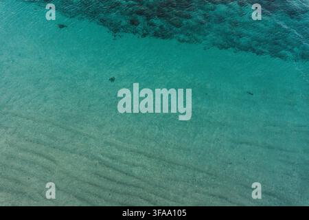 Turquoise shallow seawater with sandy seabed, subtle wave patterns, and natural underwater texture Stock Photo