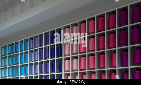 Organized display of colorful thread cones. Textile manufacturing, fashion design, haberdashery retail concept. Stock Photo