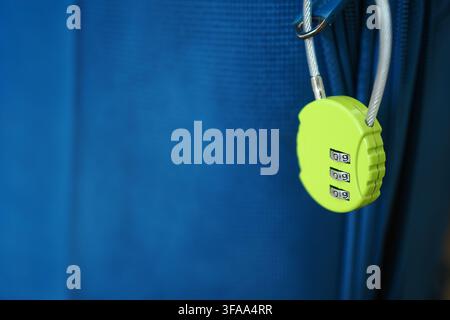 Lock hanging on a blue suitcase by a cable Stock Photo