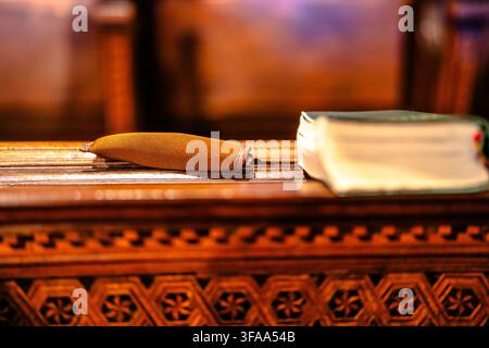 Closed book and small fabric case resting on an ornate wooden surface in warm indoor light, photographed with shallow depth of field and a softly blur Stock Photo