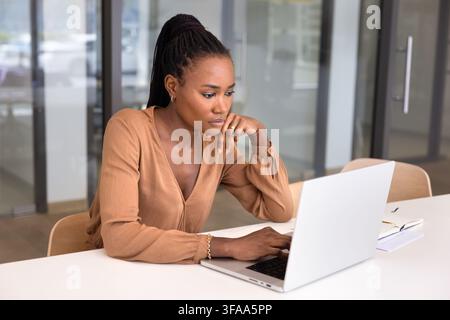 Focused businesswoman working on laptop in office Stock Photo