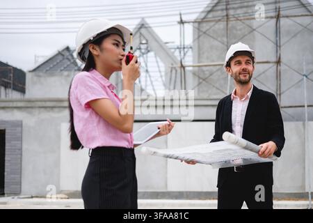 Engineers team discussion inspection at house construction site reveals a mix of modern architectural structures in progress, project collaboration Stock Photo