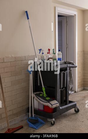 A cleaning supplies cart stands in a hotel corridor, equipped with various cleaning agents and tools, highlighting maintenance efforts in hospitality Stock Photo