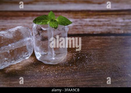 Melting ice cubes with a green mint leaf on a wet wooden surface, symbolizing coolness and refreshment Stock Photo