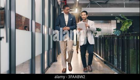Walking, hallway and business men on tablet for talking, meeting and update for finance review. Office, team and people on tech for online report Stock Photo