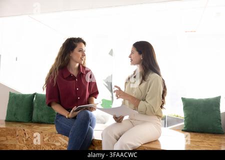 Colleagues sitting in coworking office, discussing documents, working on project Stock Photo