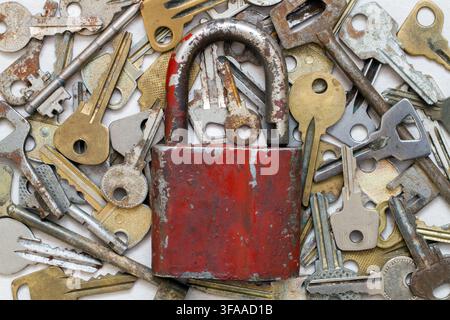 An old padlock against the background of old keys. Lots of metal keys and padlock. Stock Photo
