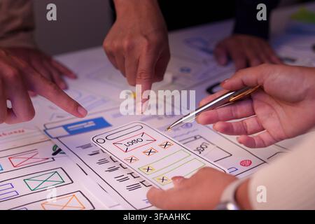 Designers pointing at mobile application wireframe layout during UX UI brainstorming session Stock Photo