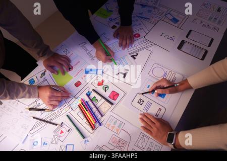 Creative design team drawing mobile app UX UI wireframes on paper during brainstorming meeting Stock Photo