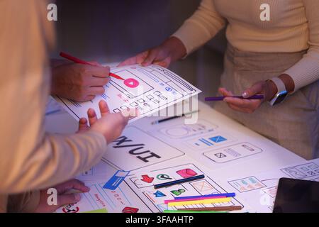 Web designers holding and reviewing paper UX UI app wireframe sketches in office meeting Stock Photo
