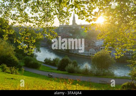 Sunset view over Bern old town city skyline and Aare river framed by green trees, Switzerland. Stock Photo