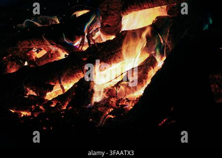 Close-Up of Glowing Embers and Burning Wood Logs in a Campfire at Night Stock Photo