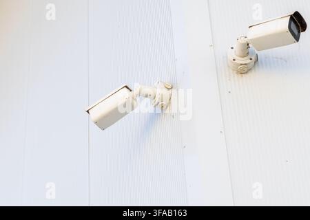 Two surveillance cameras are attached to a textured exterior wall, suggesting a focus on security and monitoring Stock Photo