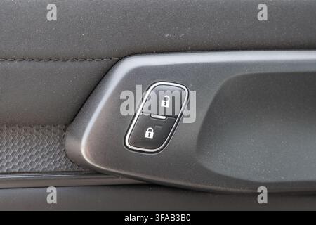 Detailed view of the interior door handle and integrated lock-unlock buttons on a modern vehicle's cabin Stock Photo