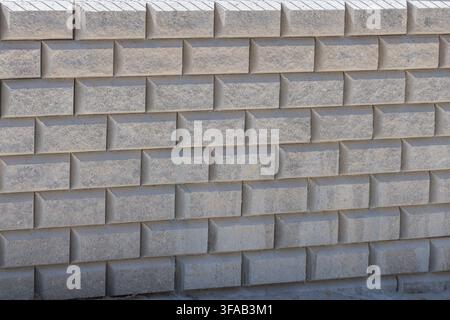 A close-up view of a modern retaining wall constructed from interlocking gray concrete blocks with a textured surface Stock Photo