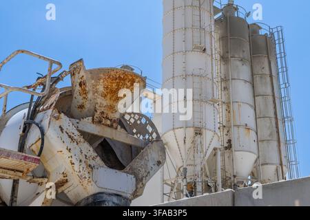 A close-up view of a concrete mixer truck's hopper and large industrial silos used for storing construction materials Stock Photo