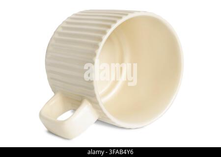 Empty ribbed ceramic beige cup lying on white background Stock Photo
