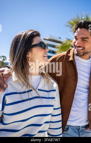 Young couple looking at each other outdoors in sunny urban setting Stock Photo