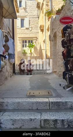 A narrow, sunlit stone alleyway with steps running up between historic stone buildings in an old Mediterranean coastal town. Stock Photo