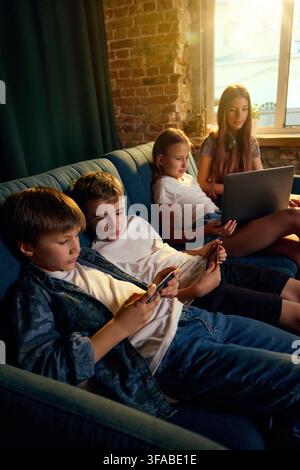 Children using smartphones and laptop together in connected home setting Stock Photo