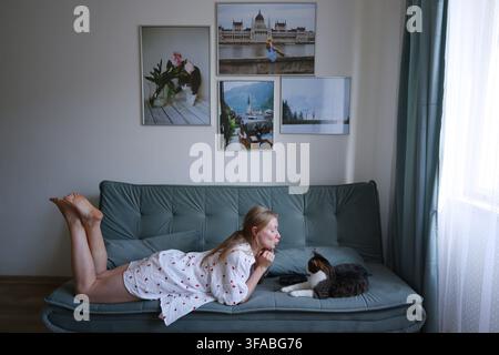 Woman relaxing on couch and interacting with her cat, showing affection and companionship at home. Stock Photo