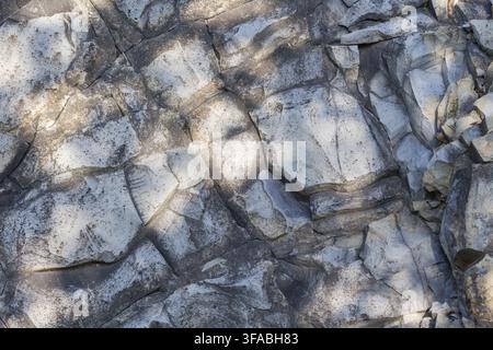 Rock surface forming a natural stone background with cracks and textured patterns. Stock Photo