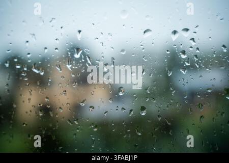 View of raindrops on a glass window pane with a blurred background in Riga, Latvia. Stock Photo