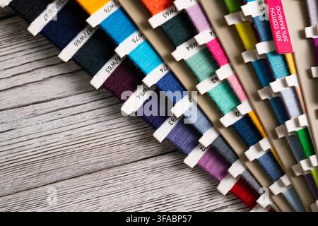 Colorful sewing threads arranged on a rustic wooden surface, creating a vibrant textile craft background with ample copy space for creative designs an Stock Photo