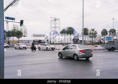 The image shows cars driving through an intersection on a rainy day with light traffic in Udon Thani Province, Thailand, on August 2, 2026. Stock Photo