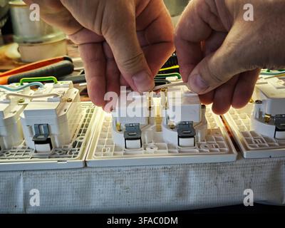 Hands are connecting electrical components in a junction box while preparing for proper electrical installation and safety measures. Stock Photo