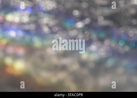Blurred Silver Reflective Surface With Scattered Rainbow Highlights Filling Frame, Showing Soft Multicolor Bokeh, Diffuse Shimmer And Abstract Luminous Texture In Close View. Stock Photo