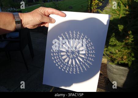 Partial solar eclipse viewed through a colander Stock Photo