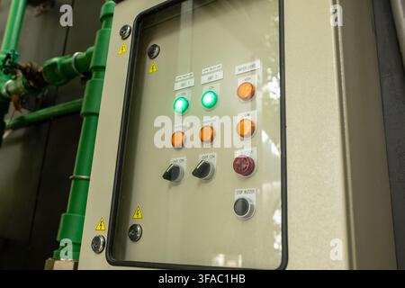 Close-up of industrial electrical control panel showing indicator lights, switches and warning labels behind glass door, automation equipment concept Stock Photo