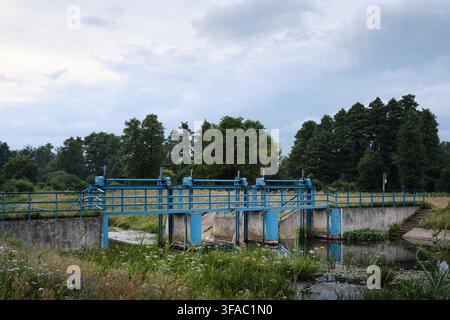 Small weir and sluice gates in a green landscape on the Rawka River in Bolimowski Landscape Park, Poland. Stock Photo