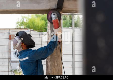 Construction worker using an angle grinder on a building structure outdoors Stock Photo