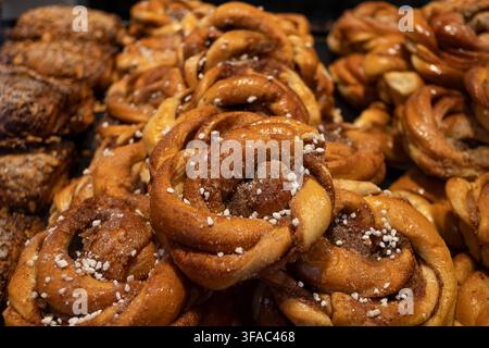 Fresh traditional Scandinavian cinnamon rolls arranged in a bakery display, golden brown pastries topped with pearl sugar, filled with aromatic spices Stock Photo