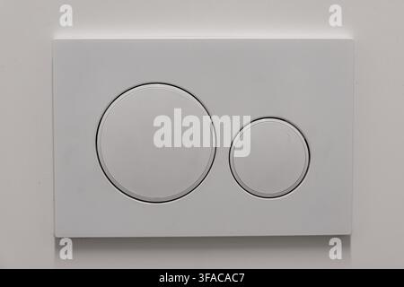 Close-up view of a contemporary silver dual flush toilet actuator plate featuring two distinct circular buttons for water saving Stock Photo