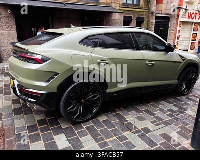 Liverpool, UK - May 16, 2026: Matte green Lamborghini Urus luxury SUV parked on a wet Liverpool street beside shops and cobbles. Stock Photo