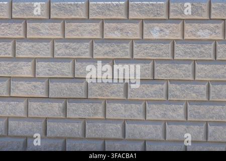 A close-up view of a wall constructed from rectangular concrete blocks with a rough texture and beveled edges Stock Photo