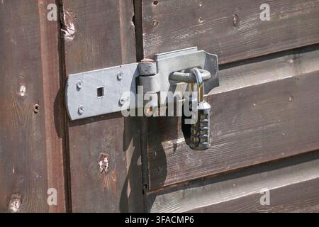 Combination lock on a shed door, locked, silver, grey, brown, shiplap wood Stock Photo