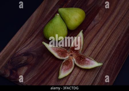 Fresh figs and a sliced fig on a wooden board Stock Photo