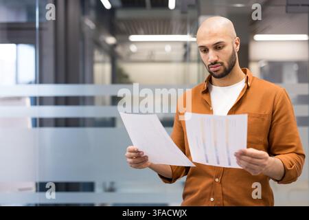 Business professional studying reports and charts in a modern office, focused on analysis and strategic planning, reviewing data for problem-solving, growth and decision making Stock Photo