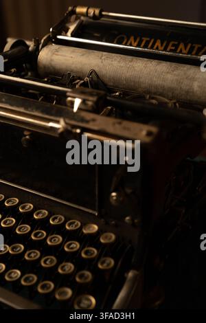 Vertical three-quarter shot of an antique mechanical typewriter showcasing its round circular keys in the foreground leading towards the metal platen Stock Photo