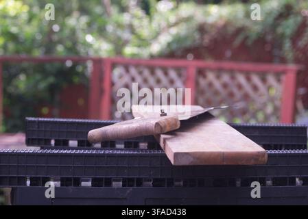 Close-up view of an old rusty hand saw resting on a wooden board outdoors, evoking traditional woodworking, carpentry, DIY projects, and manual crafts Stock Photo