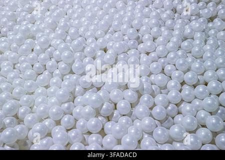A dense pile of white plastic ball pit balls fills the frame, a close up abstract texture view captured here recently today. Stock Photo