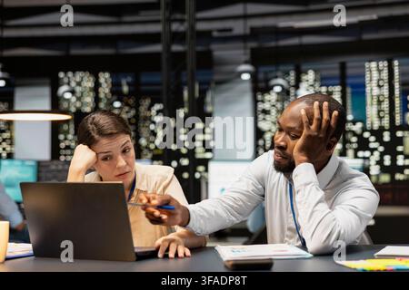 Missing project deadline, laptop and multiracial team of employees in office feeling upset. Analyzing company revenue, notebook and teamworking colleagues saddened by poor quarterly sales Stock Photo